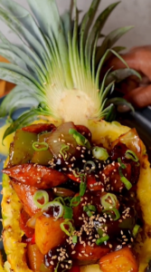 A pineapple with meat and vegetables on top of it.